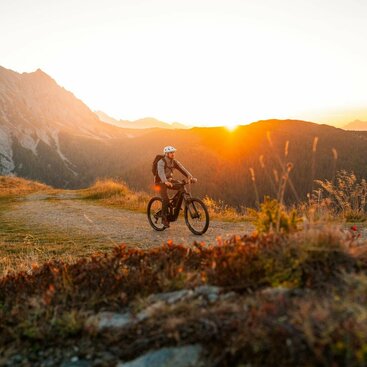 Mountainbiker bei Sonnenuntergang im Herbst auf Berg