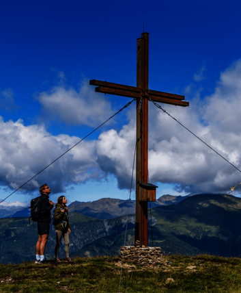zwei Wanderer bestaunen Gipfelkreuz Dorfberg